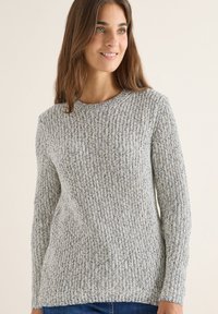 Pull en tricot gris avec une texture côtelée, un col rond et des manches longues. Le matériau présente un mélange de teintes claires et foncées.