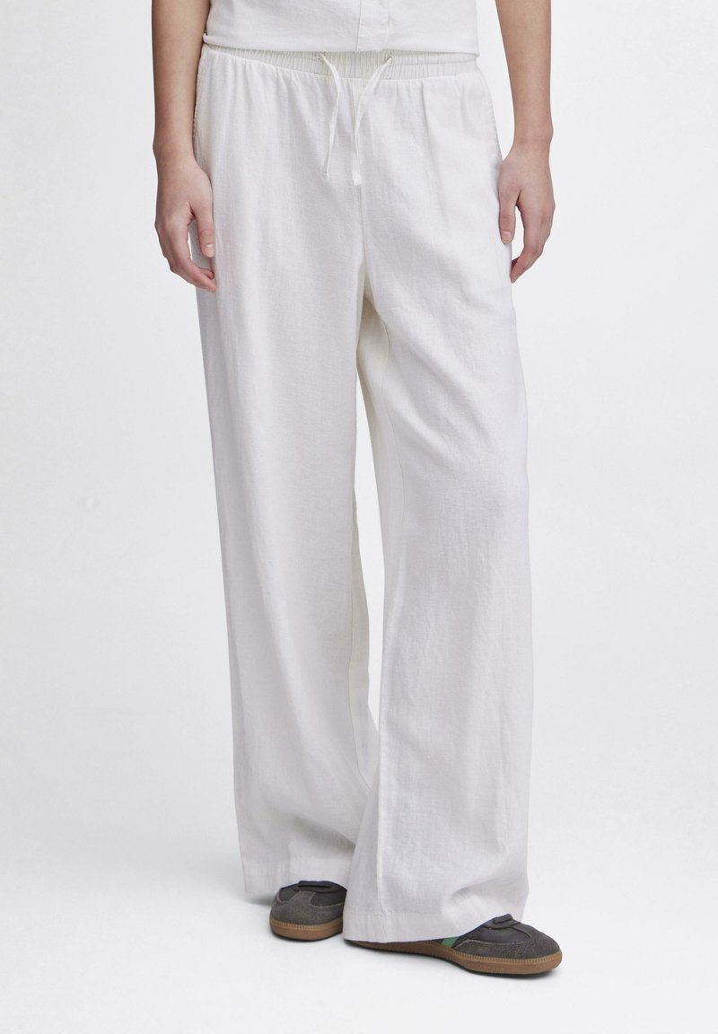 Pantalons larges en lin blanc avec une taille élastique et un cordon de serrage. Tissu léger avec une surface légèrement texturée.