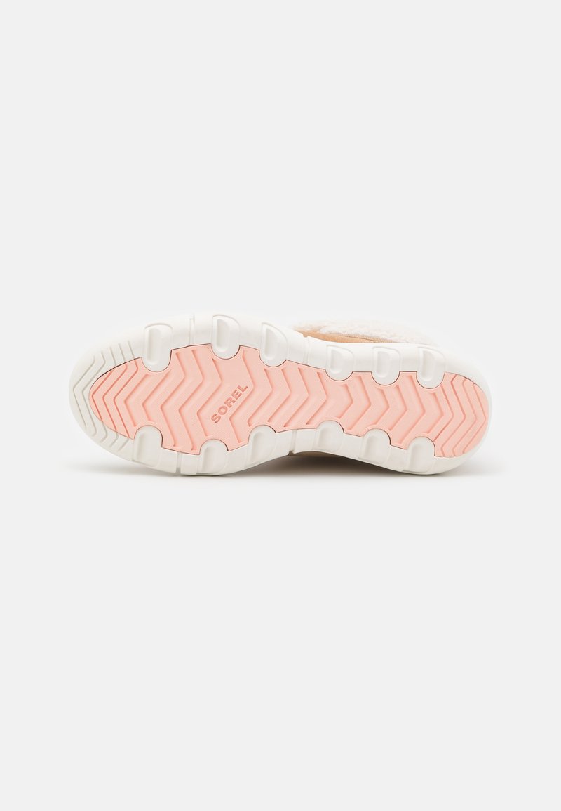 Chaussures Sorel avec une semelle en caoutchouc blanche et rose, un motif de bande de roulement en zigzag et une texture douce sur le dessus, arborant le logo de la marque sur la semelle extérieure.