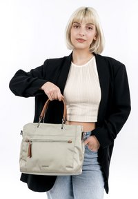 Lichtgrijze totebag met een rits voorvak, bruin leren handvatten en zilverkleurige hardware, weergegeven tegen een witte achtergrond.