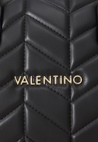 Černá kožená kabelka s chevronovým prošíváním a zlatým logem "VALENTINO". Hladký povrch s patrnými detaily prošívání.