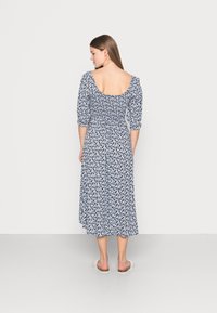 Vestido de estampado floral com fundo azul-marinho e flores brancas, corpete justo, decote quadrado nas costas, mangas três quartas e saia esvoaçante.