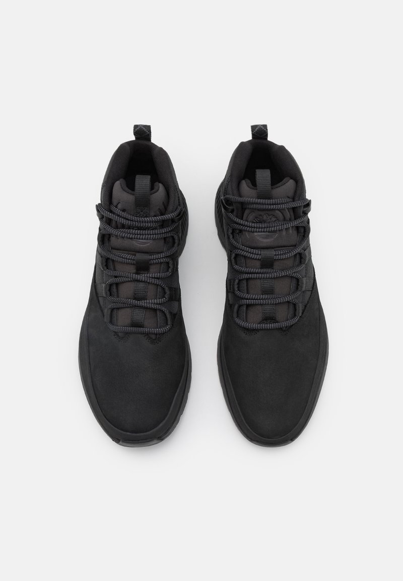 Czarne buty sportowe z gładką zamszową cholewką, wyściełanym kołnierzem, teksturowanymi sznurówkami i okrągłym noskiem. Podeszwa jest płaska i trwała.