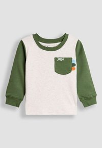 Vaaleanharmaa pitkähihainen T-paita oliivinvihreillä hihoilla, jossa on rinnassa tasku, jossa lukee "Jojo" ja värikkäitä koristeita. Pehmeä puuvillakankainen materiaali.
