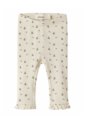 Leggings bébé côtelés couleur crème avec petit imprimé floral foncé et ourlets à volants, pliés avec étiquette de marque Lil'Atelier visible.