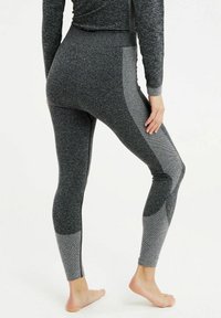 Leggings a vita alta in un tessuto a maglia nero e grigio, caratterizzati da pannelli laterali testurizzati e una finitura liscia lungo le gambe.