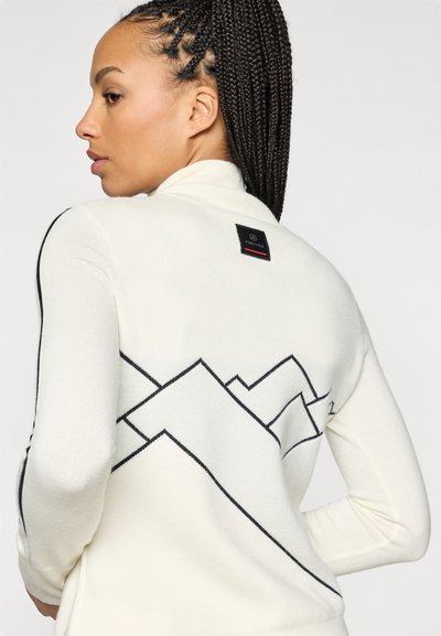 Λευκό πούλεν με ψηλό γιακά που διαθέτει μαύρα μοτίβα ορεινών γραμμών και ετικέτα λογότυπου στο πίσω μέρος; μαλακό, υφασμένο υλικό με υφή.