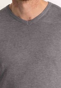 Pull gris à col en V en tissu tricoté doux avec col côtelé. Présente un design simple avec une texture lisse et une coupe ajustée.