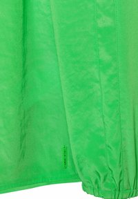 Heldergroene sportshirt met een gladde textuur, bijeen geraapte mouwen en een label met de tekst "Made in Sports."