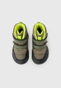 Botas de senderismo verdes y negras con una suela de goma texturizada, dos correas ajustables y un forro amarillo brillante.