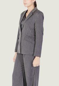 Completo grigio a righe sottili realizzato in tessuto strutturato, dotato di un blazer strutturato con rever a punta e pantaloni a gamba larga.