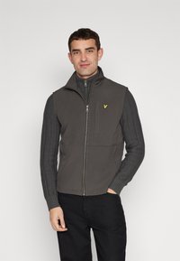 Gilet grigio con colletto alto e chiusura a zip, con maniche a coste grigio scuro. Piccolo logo giallo sul lato sinistro del petto, texture del tessuto liscia.