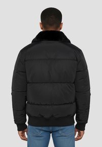 Veste matelassée noire avec col en fausse fourrure, dotée d'un design matelassé, de poignets élastiques et d'un ourlet côtelé. Vue de dos affichée.