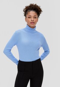 Himmelblauer, gerippter Rollkragenpullover mit langen Ärmeln, kombiniert mit schwarzen, eng anliegenden Hosen, die eine glatte Textur und einen enganliegenden Sitz zur Schau stellen.