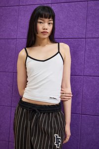 White tank top with black trim, featuring text "lets trans..." and paired with black and white pinstriped sweatpants, set against a purple background.