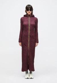 Langes, wattiertes Kleid in Burgunderrot mit Kapuze und durchgehendem Goldreißverschluss. Die Textur ist gesteppte mit ausgeprägten, hervorstehenden Nähten.