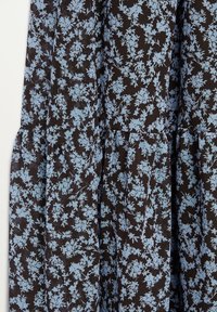 Tissu noir avec petit motif floral bleu clair et détails de coutures froncées.