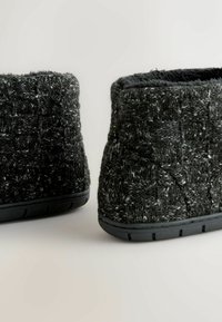 Zwarte en grijze gebreide laarzen met een gestructureerd patroon, ronde vorm en rubberen zool. Zachte binnenvoering, ontwerp van gemiddelde hoogte.