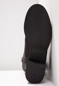 Czarne zamszowe botki za kostkę z teksturowaną gumową podeszwą, detalem w postaci zamka błyskawicznego z boku i okrągłymi wzorami na podeszwie zapewniającymi przyczepność. Rozmiar 37.