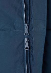 La chaqueta azul marino con cremallera presenta dos cremalleras contrastantes, una textura de tela suave y costuras reforzadas a lo largo de las uniones.