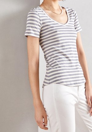Grå og hvide stribede T-shirt med korte ærmer og V-hals, tætsiddende pasform og blød tekstur. Kombineret med hvide bukser.