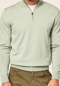 Jasnozielony sweter zapinany na zamek z wysokim kołnierzem, wykonany z miękkiego materiału, o dopasowanym kroju oraz ściągaczach na mankietach i dole. Subtelne logo.