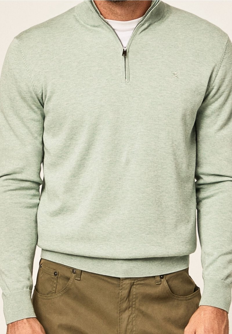 Jasnozielony sweter zapinany na zamek z wysokim kołnierzem, wykonany z miękkiego materiału, o dopasowanym kroju oraz ściągaczach na mankietach i dole. Subtelne logo.