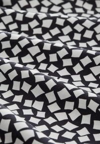 Czarna tkanina z geometrycznym wzorem białych kwadratów i rombów, o gładkiej teksturze i lekkim połysku.