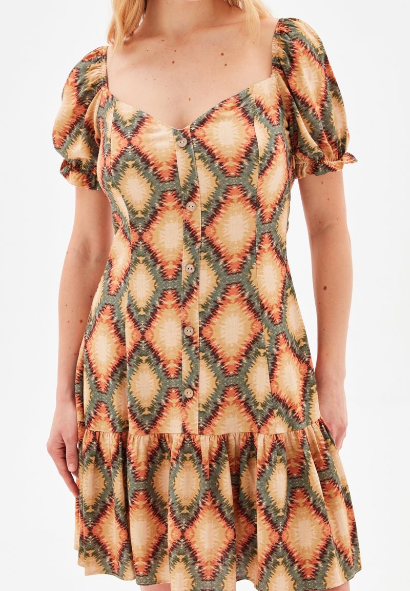 Robe à manches courtes en tissu à motifs avec de grands losanges orange, verts et crème. Devant boutonné et jupe évasée.