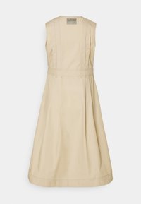 Beige väritön puuvillamekko, jossa on vartaloa myötäilevä yläosa, levenevä helma ja pienenpääkertaiset tikkaukset. Mekossa on pyöreä kaula-aukko ja huomaamaton takana oleva merkki.