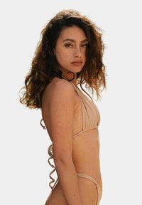 Nude bikini z halter neck, z marszczonym wykończeniem i spiralnymi sznureczkami po bokach, podkreślający gładką, smukłą sylwetkę.