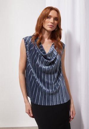 Short-sleeve, cowl neck top in navy with vertical ribbed texture. Soft material contrasts with a fitted black skirt.