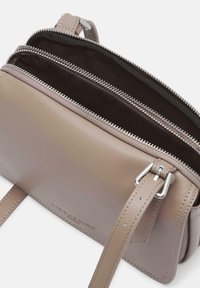 Borsa in pelle di un leggero taupe con doppie tasche con zip. Caratterizzata da hardware tono argento e una tracolla regolabile. Texture liscia.