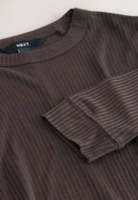 Camiseta de manga larga acanalada de color marrón oscuro con cuello redondo, manga doblada y etiqueta de la marca "NEXT" en negro dentro del cuello.