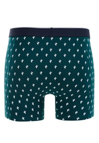 Sötétzöld boxer alsók ismétlődő fehér kaktuszmintával, egyszínű sötétkék derékpánttal és szoros illeszkedéssel. Sima szövettextúra.