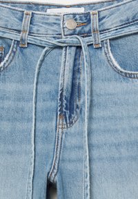 Jeans in denim azzurro chiaro con tasche frontali, cintura con bottoni e cintura in tessuto legata in vita.