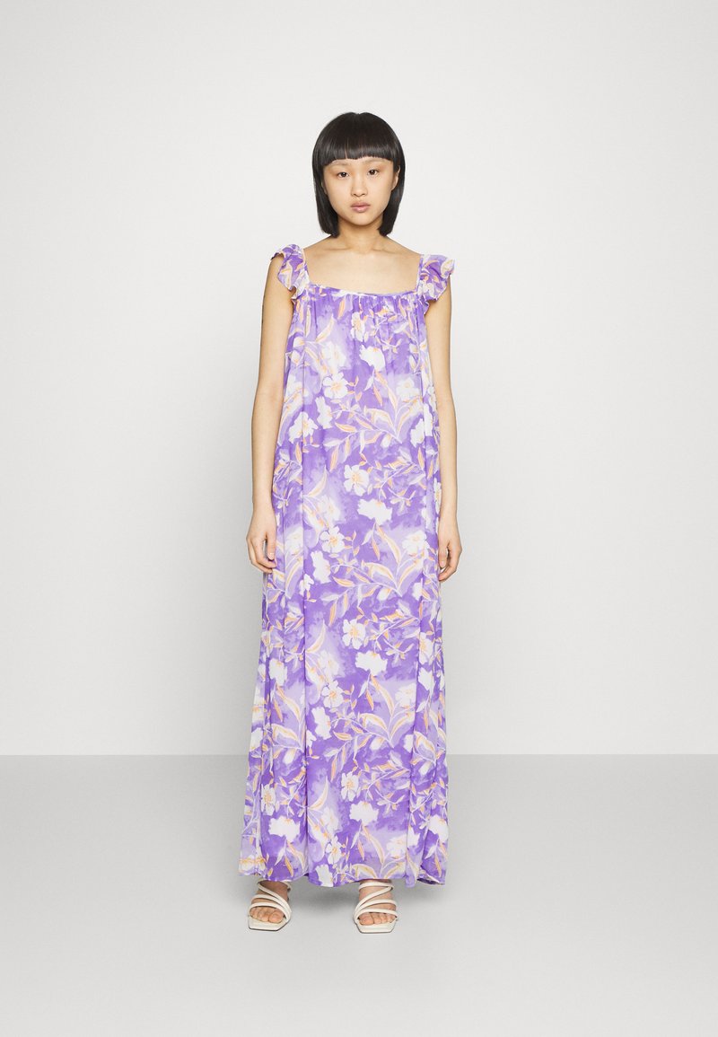Vestido maxi em tecido lilás claro, com padrões florais em tons de branco e laranja. Alças de ombro com babados acrescentam detalhe.