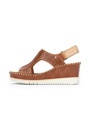 Sandale compensée en cuir marron avec design découpé, détails perforés, bride de cheville réglable et semelle en caoutchouc blanche.