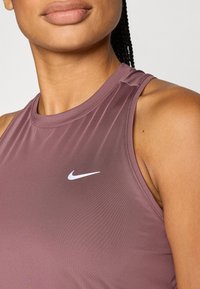 Μοβ αθλητική φανέλα χωρίς μανίκια με στρογγυλή λαιμόκοψη και μικρό λ ευκό λογότυπο Nike στην αριστερή πλευρά του στήθους. Λείο ύφασμα.