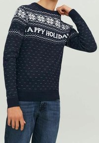 Námořnický modrý pletený svetr s bílým vzorem sněhových vloček a textem "ŠŤASTNÉ VÁNOCE", žebrované manžety a spodní lem, s texturou malých teček po celém povrchu.