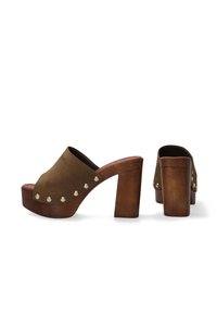 Bruine suède platform mules hebben een brede bovenkant, gouden studs langs de zijkant en een stevige houten hak voor stabiliteit.