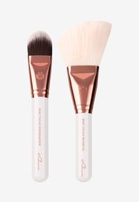 Makeup brushes with white handles and rose gold metal ferrules. One has dense black bristles; the other has wide, soft white bristles.