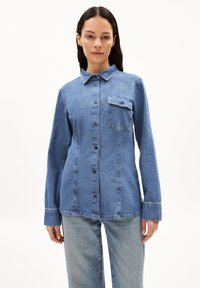 Hellblaue Denim-Hemd mit Knopfverschluss, Kragen und einer einzelnen Brusttasche. Es hat lange Ärmel und eine lockere Passform.