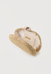 Μπεζ υφαντό τσαντάκι χειρός με κρεμ ύφασμα στο εσωτερικό, μικρή τσέπη, ετικέτα φροντίδας και μεγάλο μάρμαρο κουμπί κούμπωμα ανοιχτό σε λευκό φόντο.