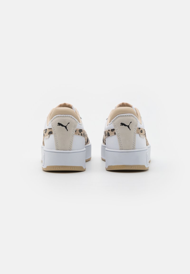 Weiße Sneaker mit beigen Akzenten, die ein strukturiertes Muster an den Seiten, eine klobige Sohle und ein schwarzes Logo an der Ferse aufweisen.