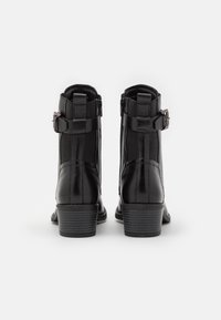 Bottines en cuir noir avec fermeture éclair, dotées de panneaux latéraux élastiques et d'un détail boucle décorative. Talon bas texturé.