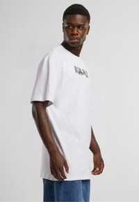 White cotton t-shirt with short sleeves, featuring a graphic print on the chest, paired with blue denim jeans. Simple, unembellished design.