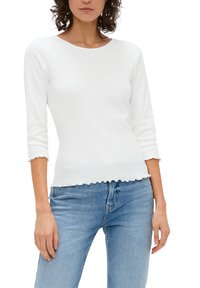 Witte geribbelde langemouwen top met een ronde halslijn, gegolfde zoom en een aansluitende pasvorm, gecombineerd met lichtblauwe denim jeans.