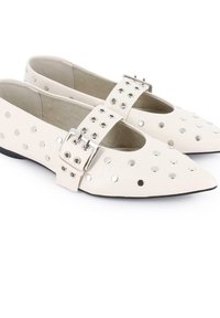 Bailarinas de cuero blanco con puntera puntiaguda, que presentan una banda ancha con una hebilla plateada y adornos de tachuelas a lo largo de los lados. Textura suave.