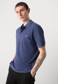 Navyblaue Polohemd mit kurzen Ärmeln und klassischem Kragen, mit einem kleinen Logo auf der Brust, aus strukturiertem Stoff.